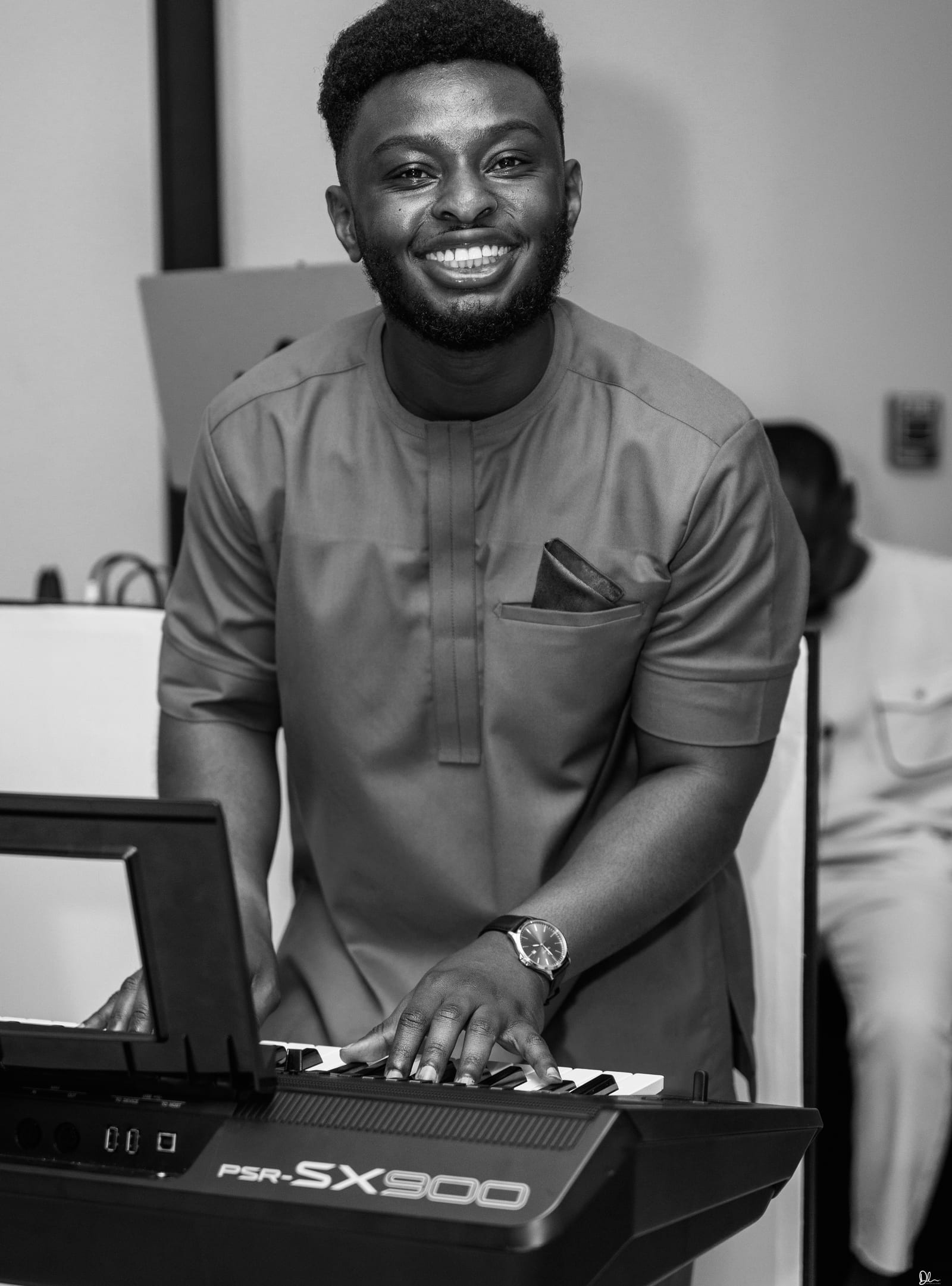 Black and white portrait of Ato Baah-Nyarkoh smiling behind a Yamaha PSR-SX900 keyboard.